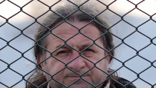 Man Looking Up Through Chain Link Fence