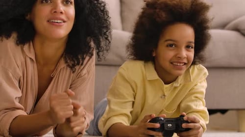 Child and Mother Play Video Games Together at Home
