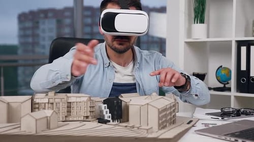 Engineer-Designer in Virtual Reality Headset Working with Model of Future Buildings in Design Studio