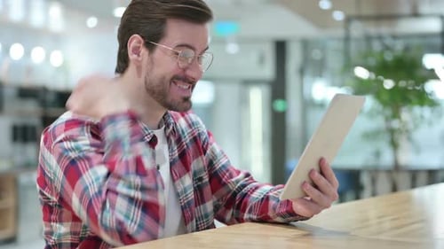 Excited Man Using Tablet in Modern Workplace