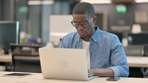 Smiling Young Adult Working on Laptop in Office