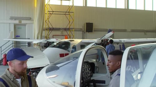 Pilot and Aircraft Mechanic Talking in Hangar