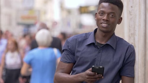 young attractive african man in the street focused on typing on smartphone
