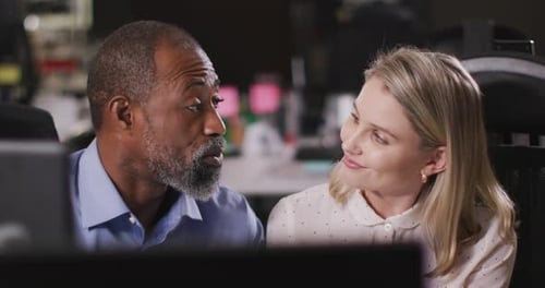 Professional businessman and businesswoman discussing while sitting in modern office in slow motion