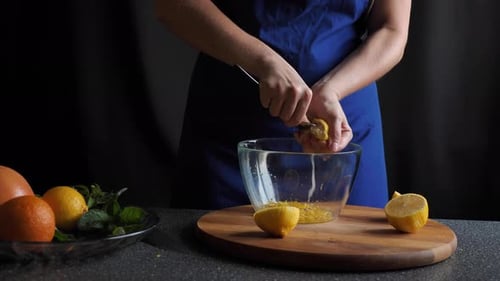 Woman Squeezing Lemon Juice into Bowl in Kitchen