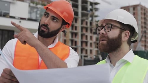 Engineers Reviewing Building Plans at Construction Site