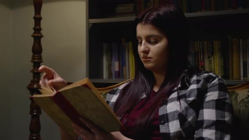 Woman Reads Book by Lamp at Home at Night