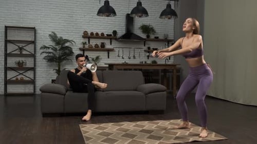Woman Doing Squats as Man Uses Megaphone