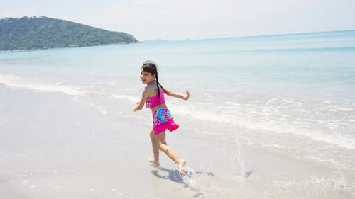 4K Portrait of little Asian girl running and playing on tropical beach in summer sunny day.
