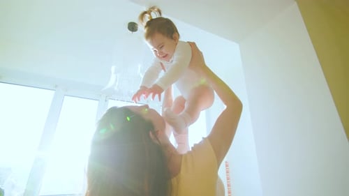Mother Lifts Smiling Infant in Bright Room