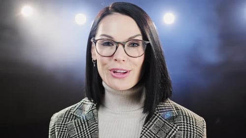 Porträt von Frauen, die im dunklen Konferenzsaal durch ein Mikrofon sprechen. Frau redet hinein