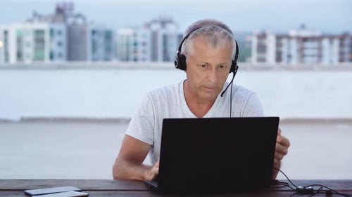 Professional Works Remotely Using Laptop and Headset