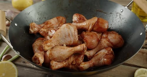 Raw Chicken Drumsticks Marinating in Wok on Table