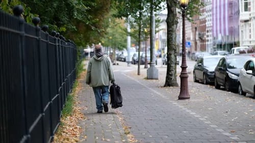 Senior Adult Walks on Urban Street in Autumn