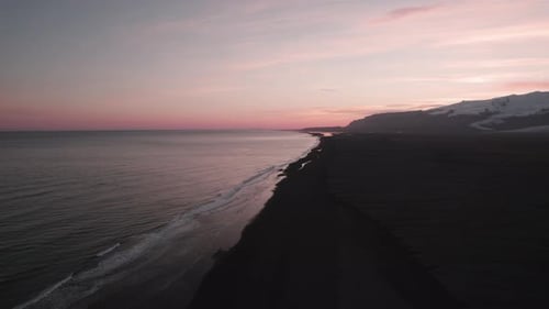 Sunset aerial over Iceland black sand beach and background mountain glacier.