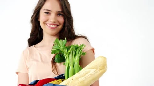 Retrato de mujer sonriente sosteniendo una bolsa de supermercado