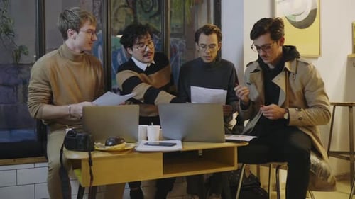 Businessmen Reading Documents in Cafe. Male Partners Discussing Business Papers