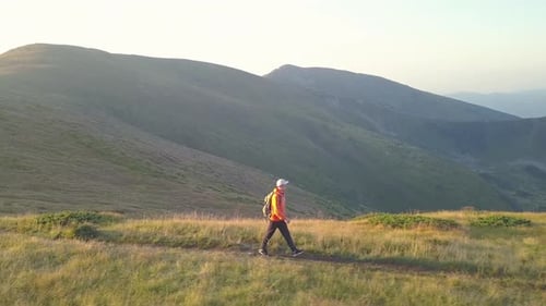 Tourist Hiker with a Backpack in Orange Jacket Walking on Mountain Path in Carpathian Mountains