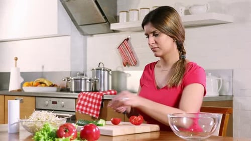 Woman Cuts Tomato in Kitchen