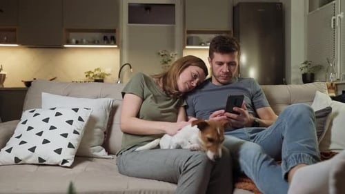 Couple Relaxing on Couch with Dog and Phone