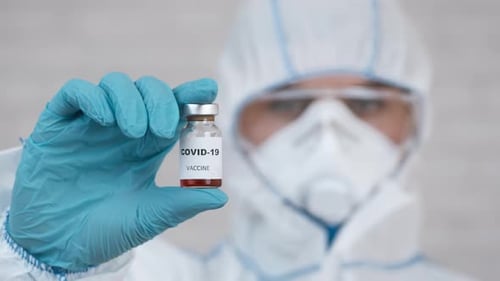 Scientist Holding COVID-19 Vaccine Vial in Hospital Setting