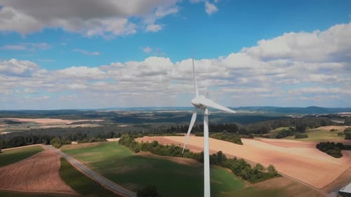 Windmühle mit riesigen rotierenden Klingen vor blauem Himmel