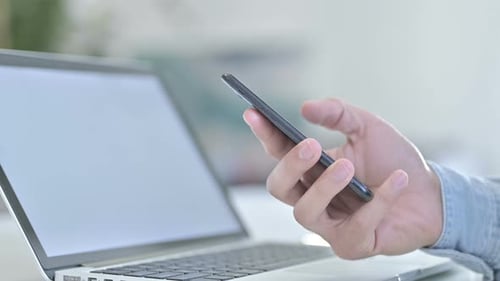 Close Up of Hand Scrolling on Smartphone on Office Desk