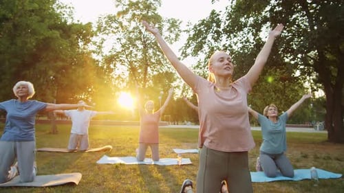 Adults and Seniors Doing Yoga in Park at Sunrise