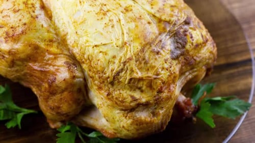 Baked Whole Chicken with Herbs and Lemon Wedges Lies on a Dark Plate with
