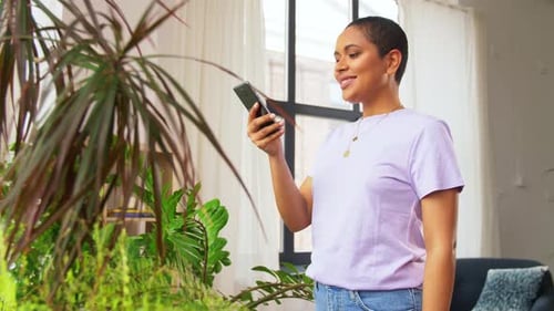 Smiling Woman Using Mobile Phone Indoors by Plants