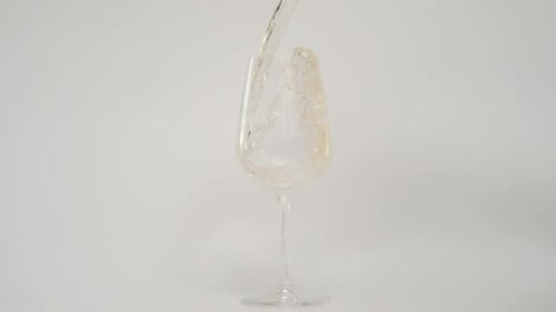 Golden Liquid Pours into Glass on White Background