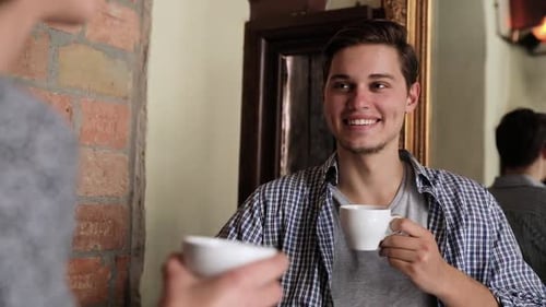 Young Man Drinking Coffee With Woman At Cafe