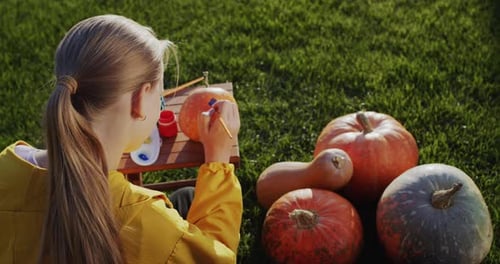 Rear View A Child Paints a Pumpkin Prepares Decorations for Halloween