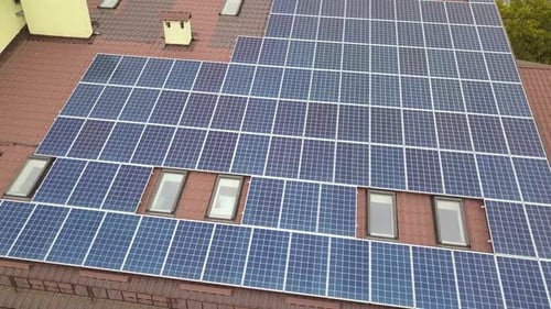 Aerial view of solar power plant with blue photovoltaic panels mounted of apartment building roof.