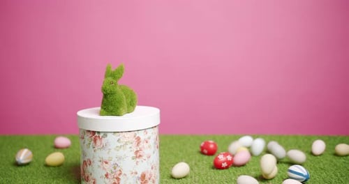 Kaninchenspielzeug auf rosa Hintergrund aus grünem Gras mit vielen farbigen Eiern