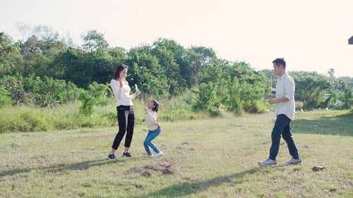 Family Playing with Bubbles on Sunny Day Outdoors