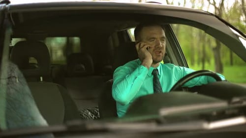 Bussinesman Sitting in Car Wearing Green Shirt and Tie Swearing By Phone