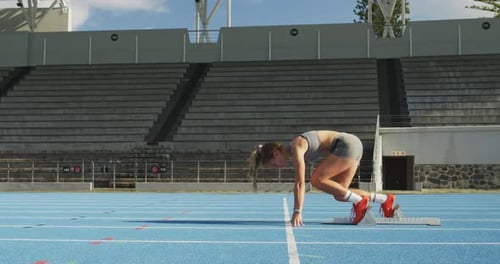 Side view of caucasian athlete preparing for race in stadium