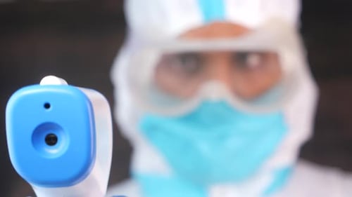 Medical Worker in Protective Suit with Thermometer