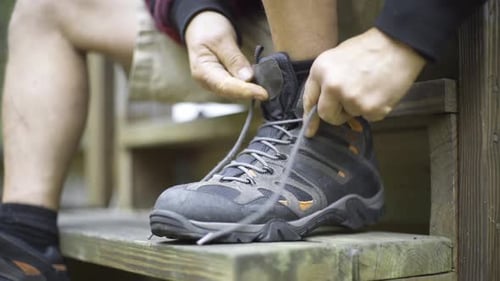 Man Tying Hiking Boot Laces on Wooden Steps