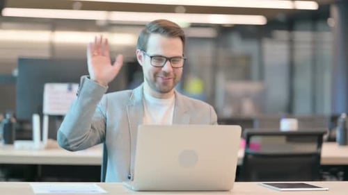 Man Waving During Video Conference in Office