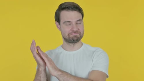 Junger Mann klatscht, applaudiert auf gelbem Hintergrund