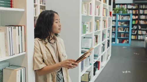Studentin liest Buch in der Bibliothek