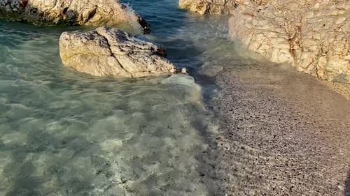 Kieselsteine, Sandstrand, Meer, Meerwasser, Wellen, runde, glatte Steine oder Felsbrocken