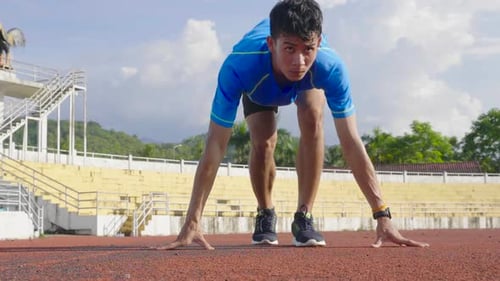 Männlicher Athlet in Startposition und läuft