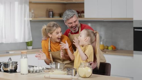 Excited Little Girl Making Flour Splash and Laughing Cooking Dough Together with Loving Parents at