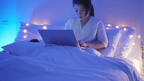 Woman Working on Laptop Computer in Bed at Night