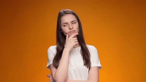 Woman Thinking with Hand on Chin Against Orange