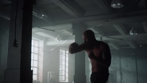 Kickboxer Fighting with Shadow in Sports Club