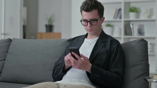 Man Cheering while Using Smartphone on Couch